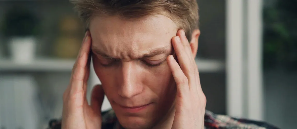 Ein Mann fasst sich mit beiden Händen an den Kopf.