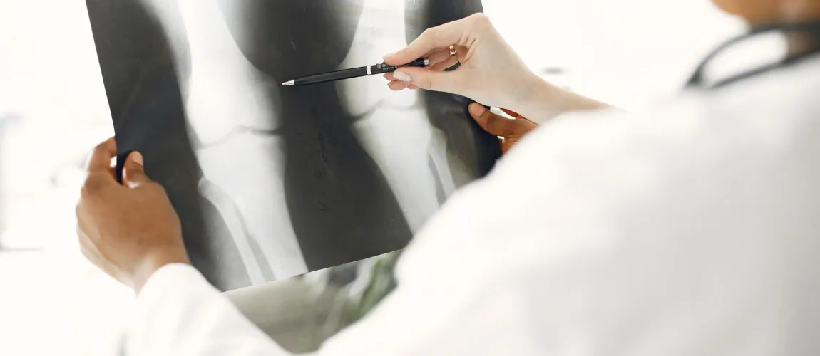 Nahaufnahme eines Röntgenbilds, eine Person zeigt mit dem Kugelschreiber darauf.