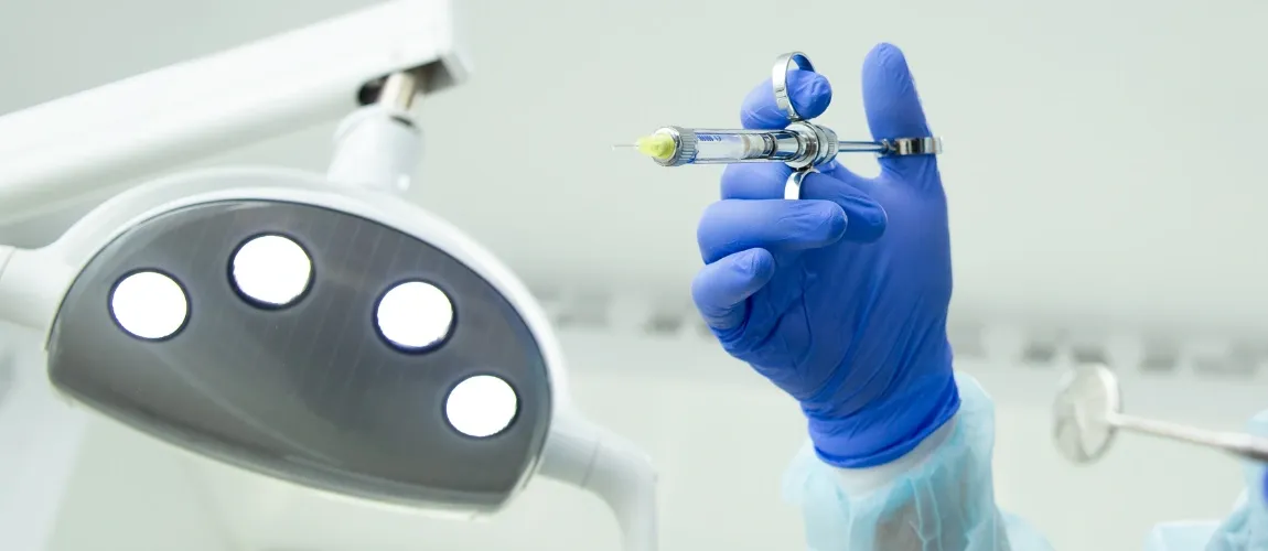 Eine Hand mit einem Handschuh bekleidet hält eine Spritze.