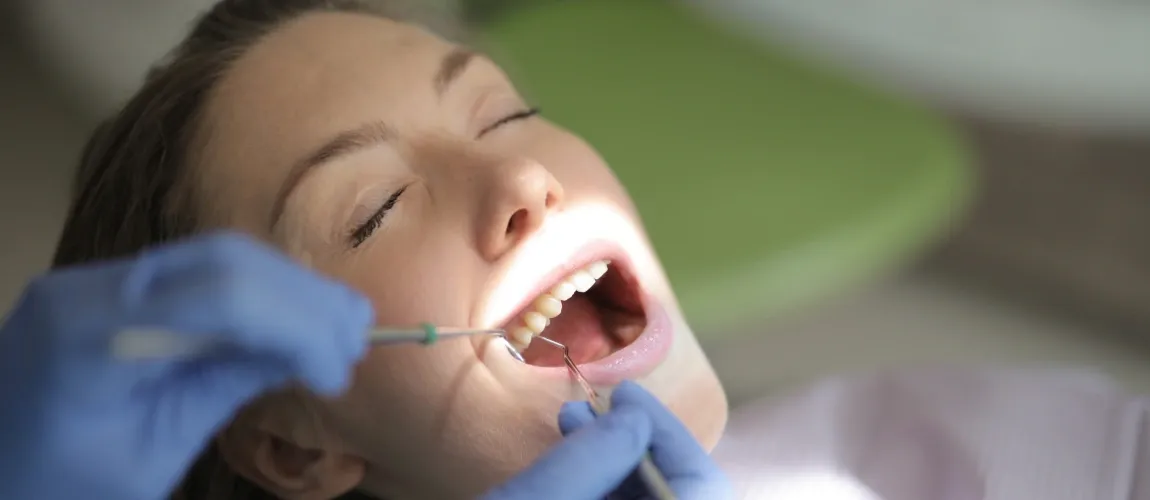 Die Zähne einer Frau werden beim Zahnarzt mit Instrumenten untersucht. 