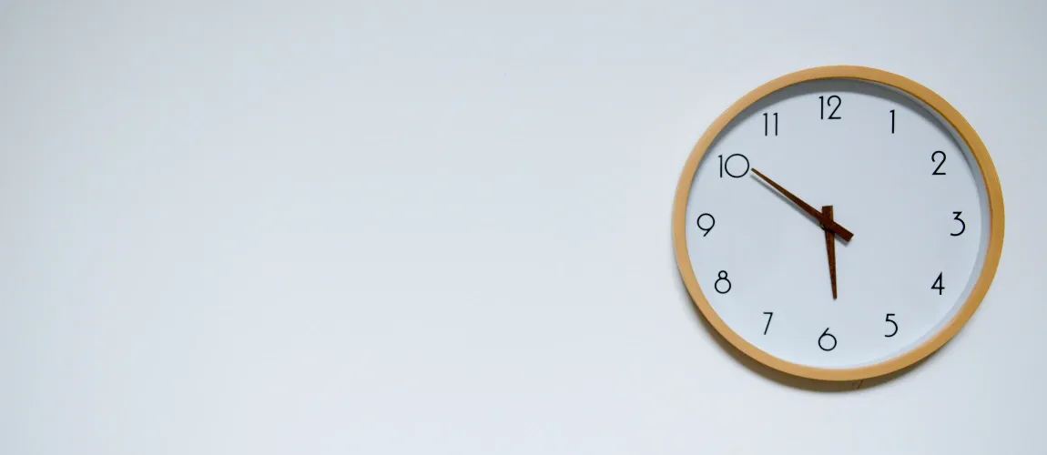 Abbildung einer Uhr, die an einer weißen Wand hängt.