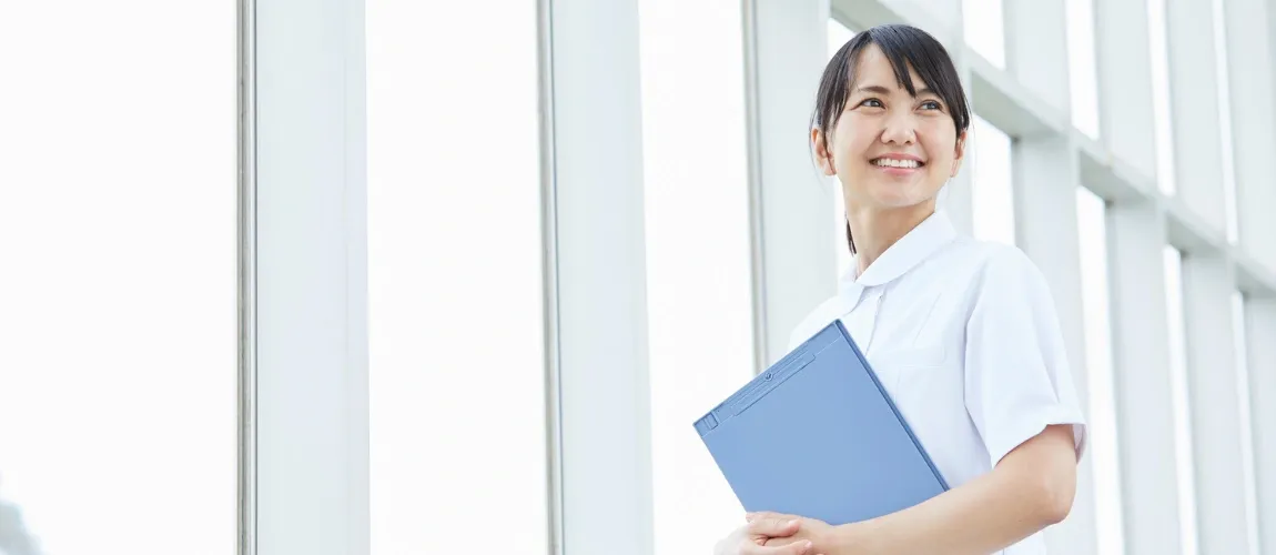 Eine Frau hält einen Hefter und blickt lächelnd zur Seite. 