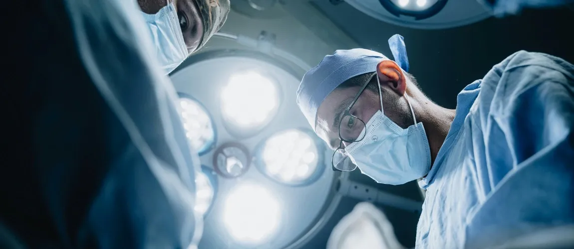 Zwei Männer stehen unter einer Operationslampe.