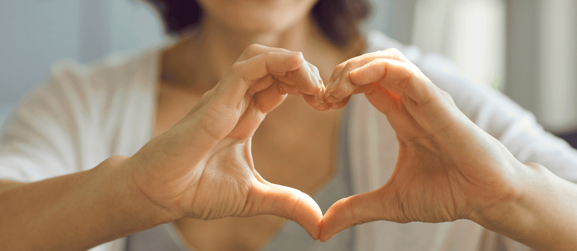 Eine Frau formt mit den Händen ein Herz.
